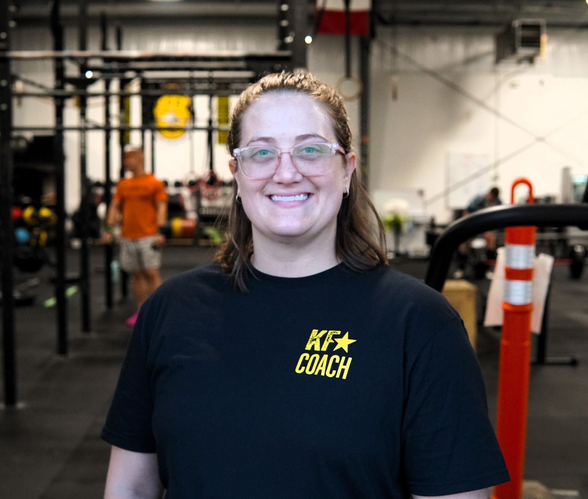 Woman in glasses smiles, wearing black 