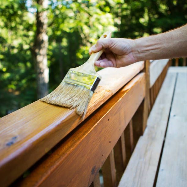 A person is painting a wooden railing with a brush.