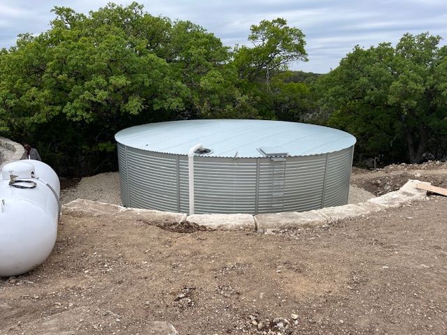 A man is standing on a ladder fixing a gutter on the roof of a house.