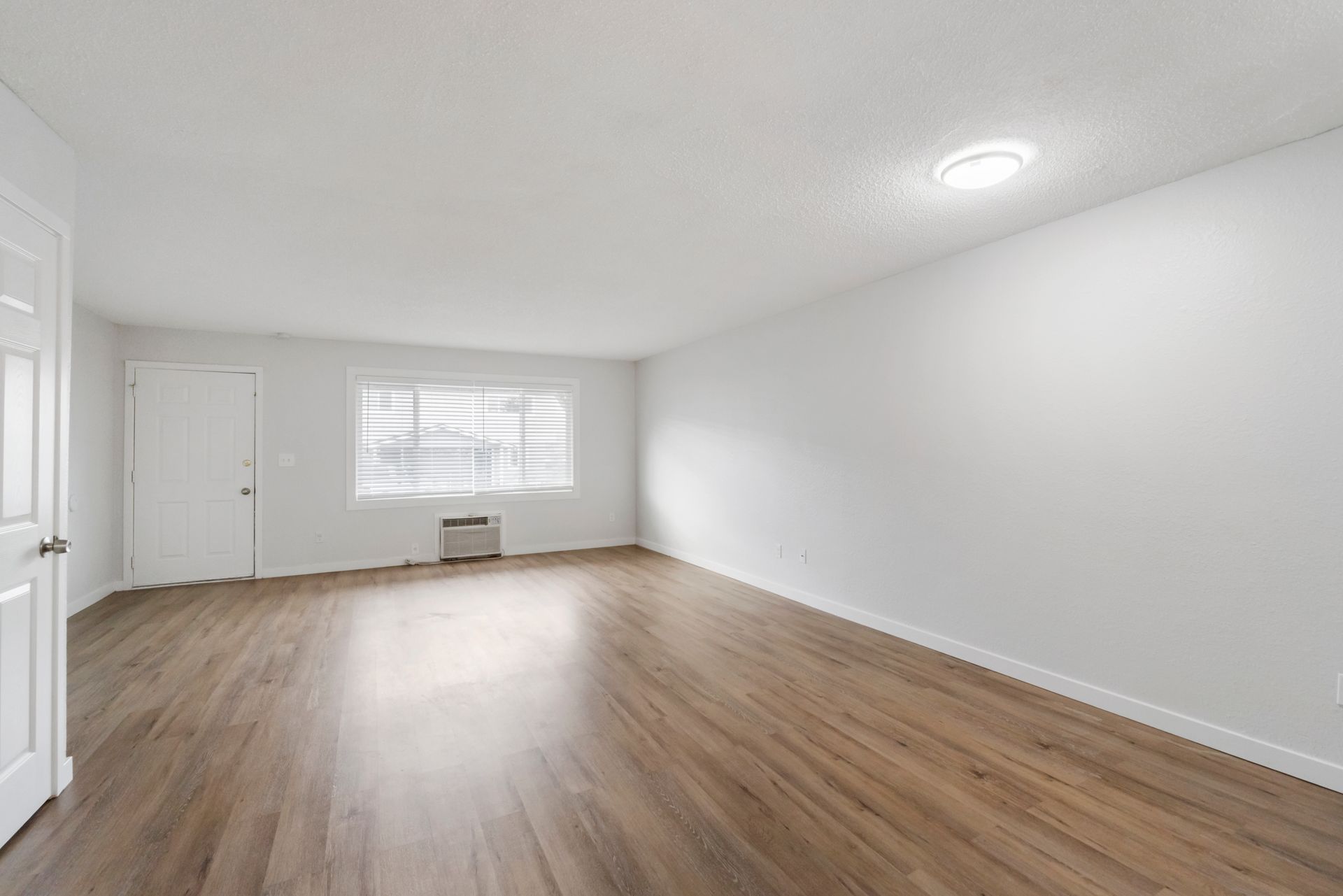 An empty living room with hardwood floors and a window.