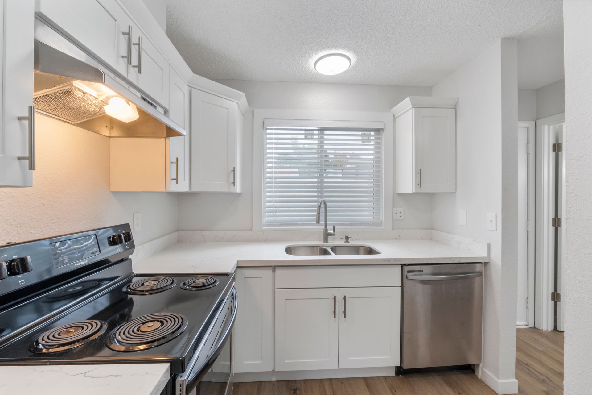 A kitchen with a stove , sink , and dishwasher.