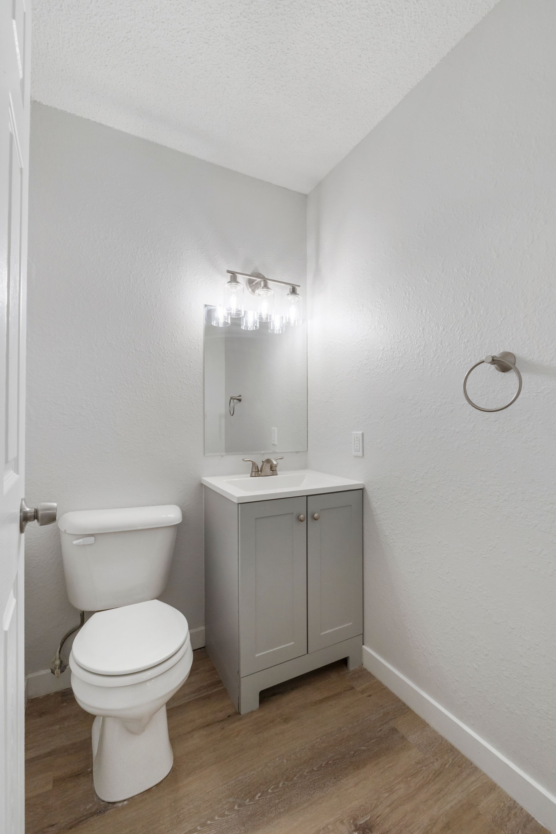 A bathroom with a toilet , sink and mirror.
