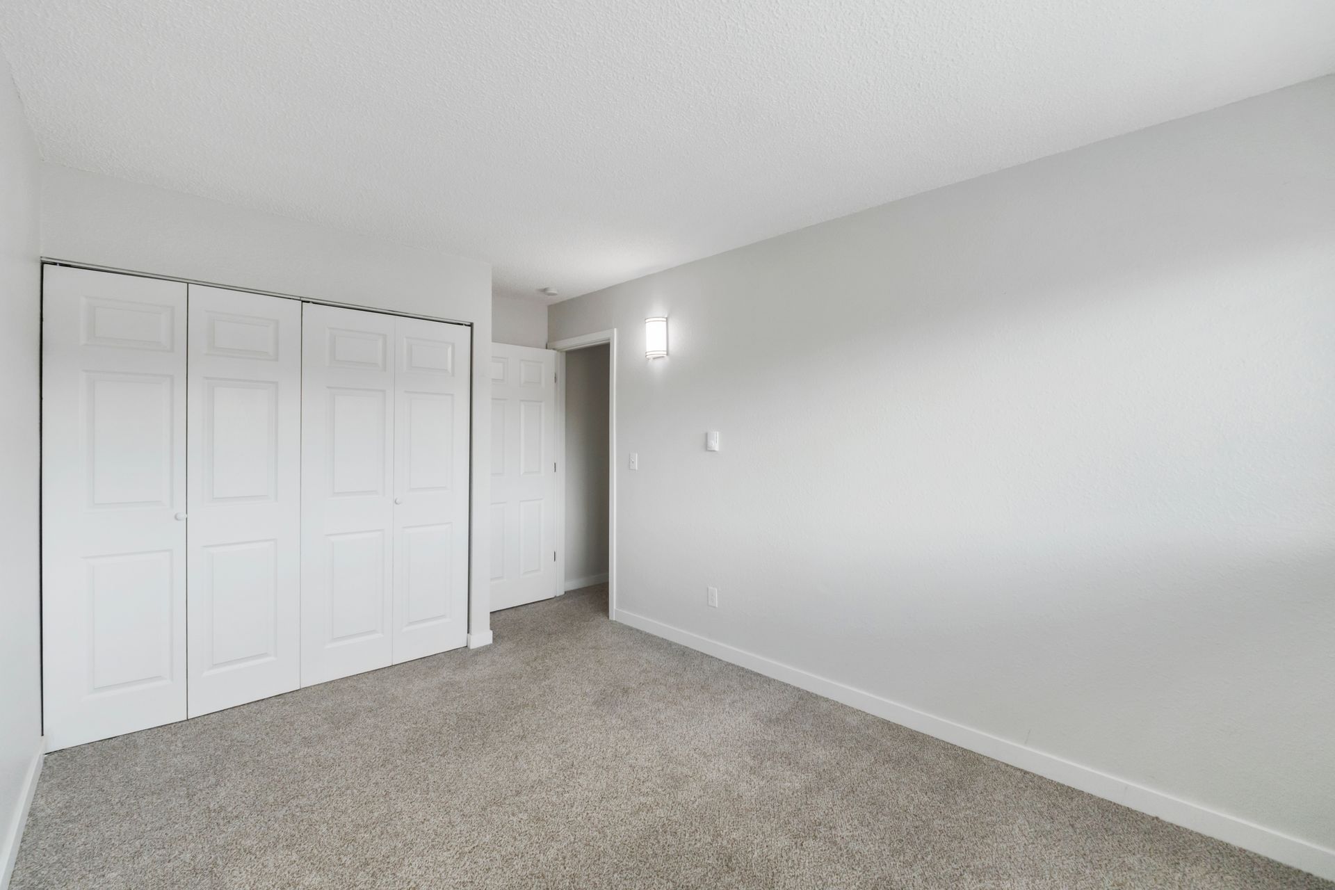 An empty bedroom with a carpeted floor and white walls.