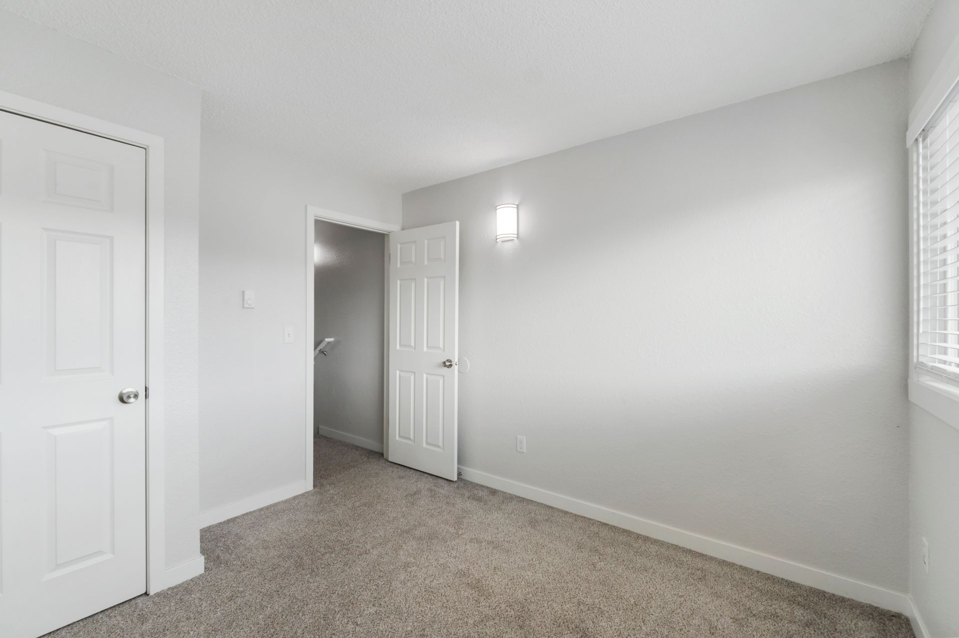 An empty bedroom with a carpeted floor and white walls.