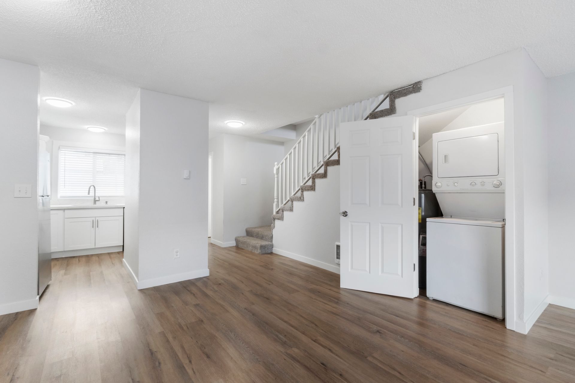 A living room with hardwood floors and a staircase in a house.