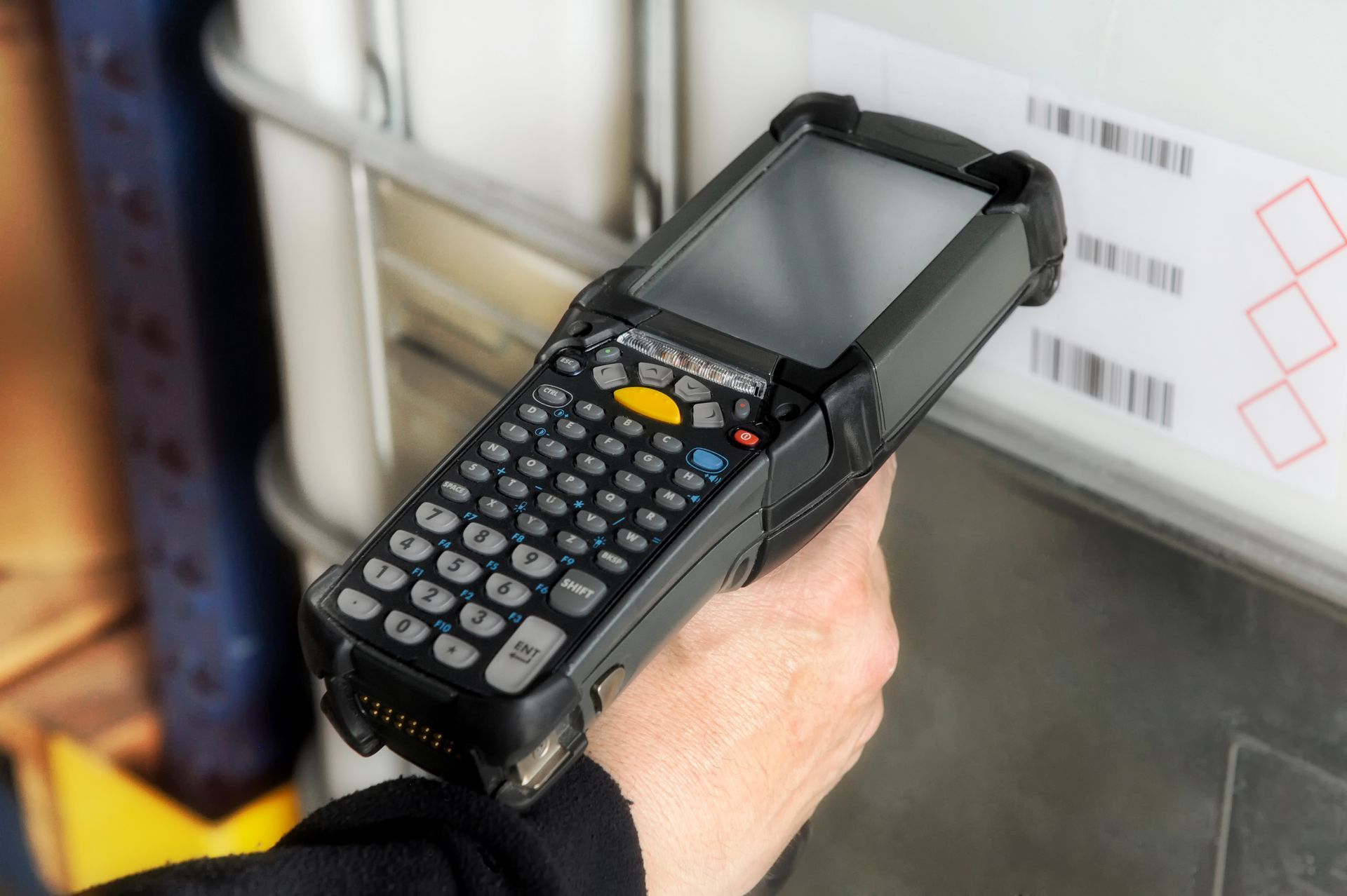 Hand scanning a barcode on a white container with a handheld device.