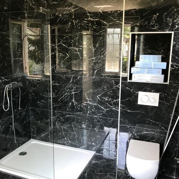 Une salle de bain avec du carrelage noir et des toilettes