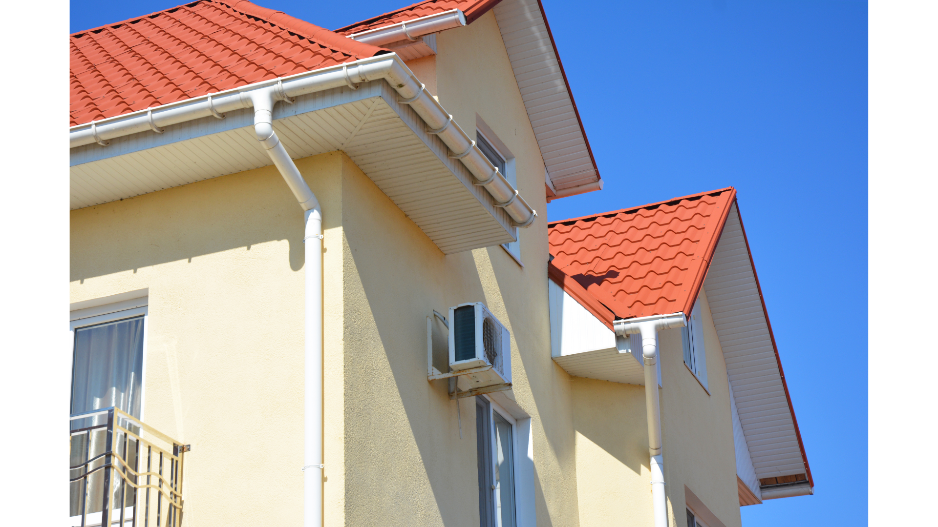 Une maison avec un toit rouge et une gouttière blanche