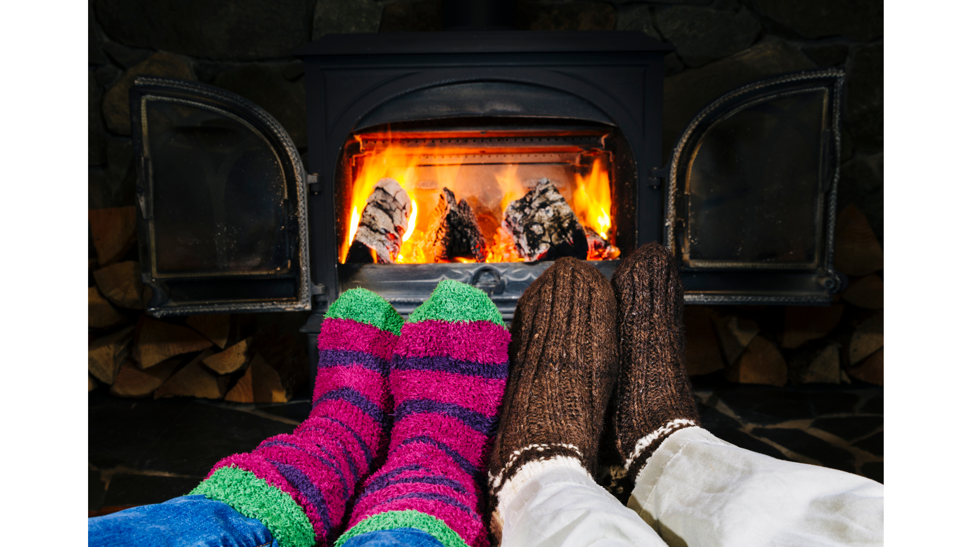 Deux personnes portant des chaussettes colorées sont assises devant une cheminée.