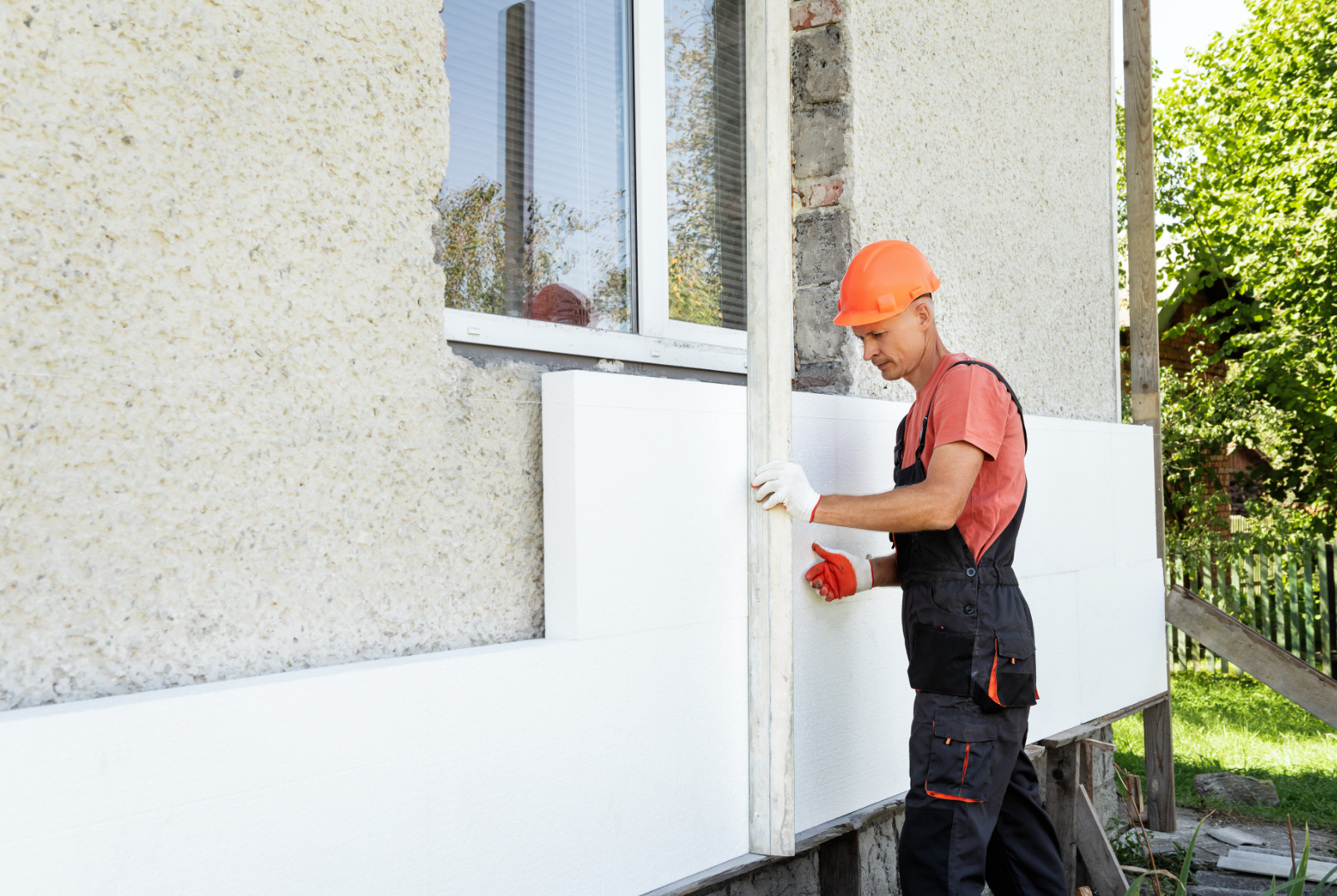 Un homme installe de l'isolant sur le côté d'un bâtiment.