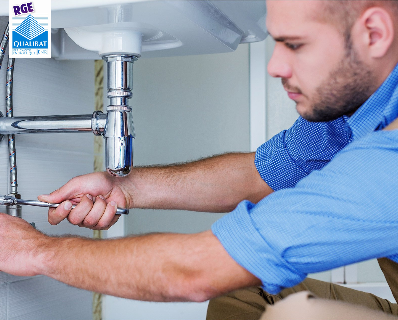 Un homme répare un évier avec une clé.