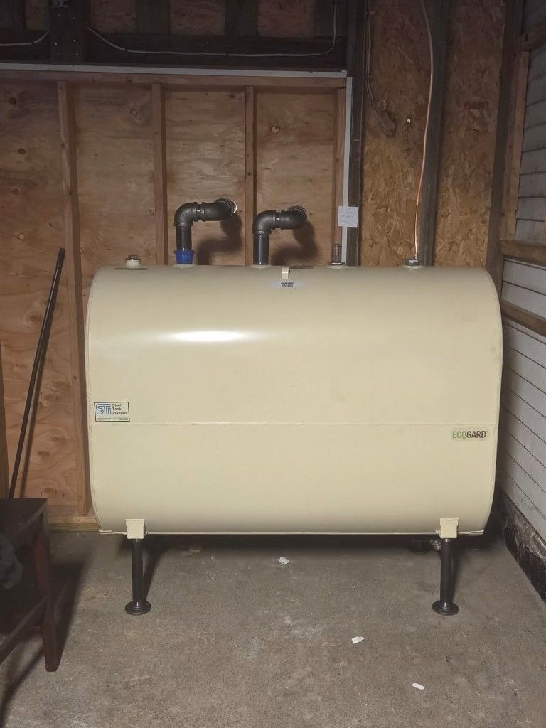A blue Buderus boiler sits in a basement with its front casing removed, exposing the burner and interior components.