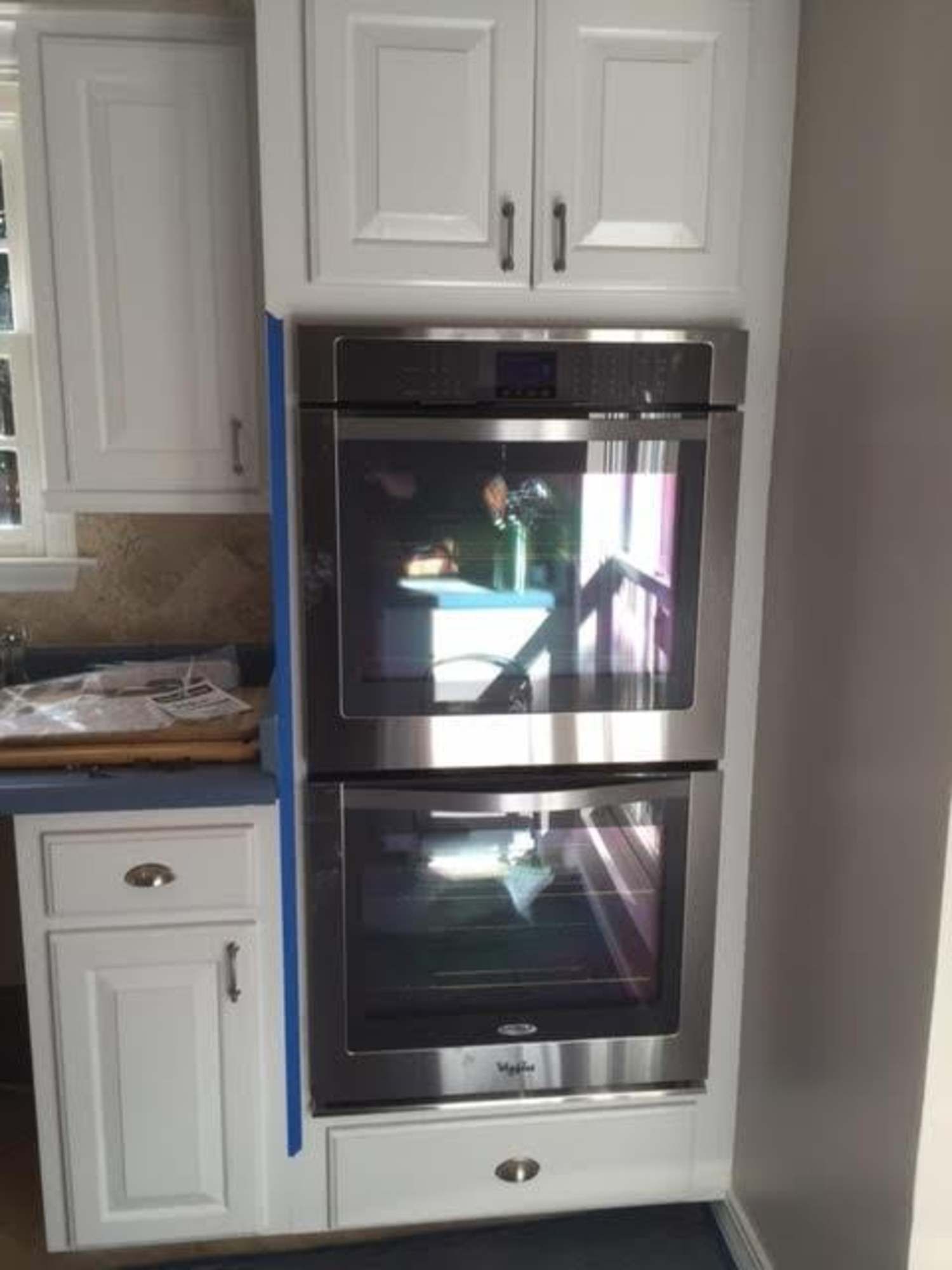 a kitchen with white cabinets and a stainless steel double oven .