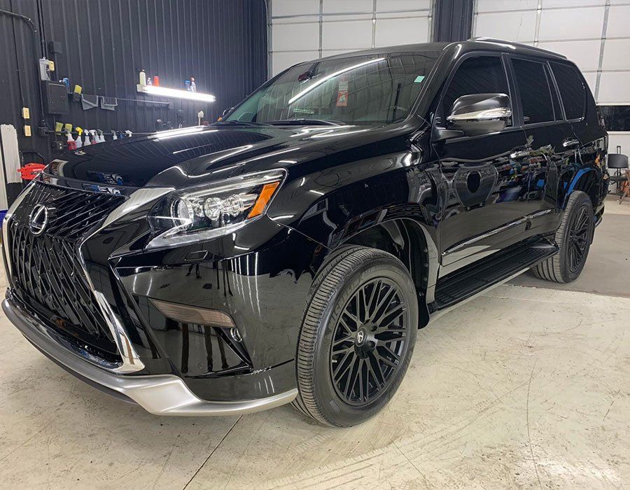 Black Lexus SUV parked inside, showcasing its glossy finish.