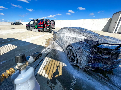 A car is being washed with foam in a parking lot.