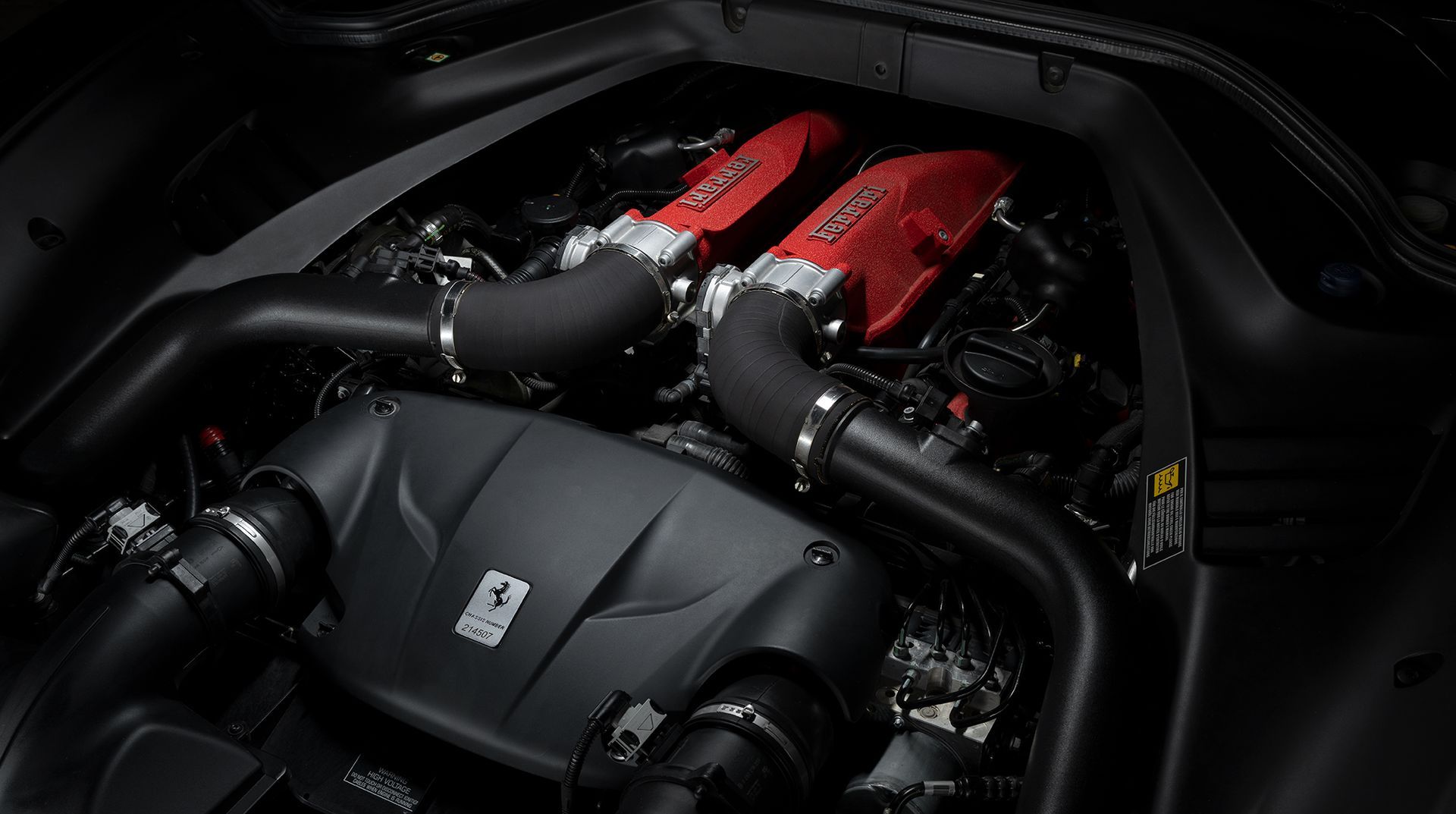 A close up of a ferrari engine in a black car.