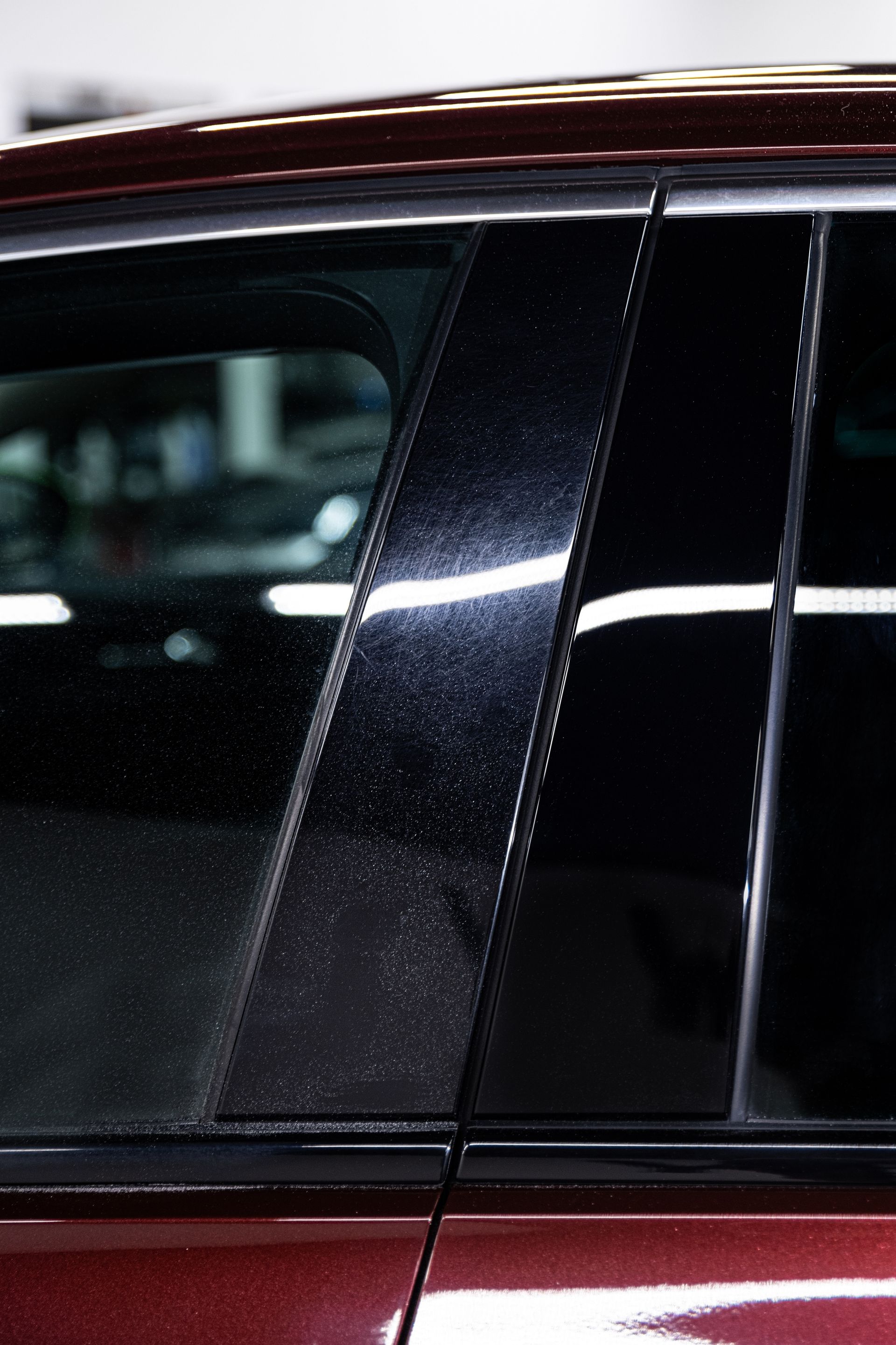 Close-up of a car's dark, shiny pillar; water droplets visible.