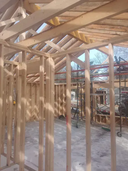 A house is being built with wooden beams and a roof.