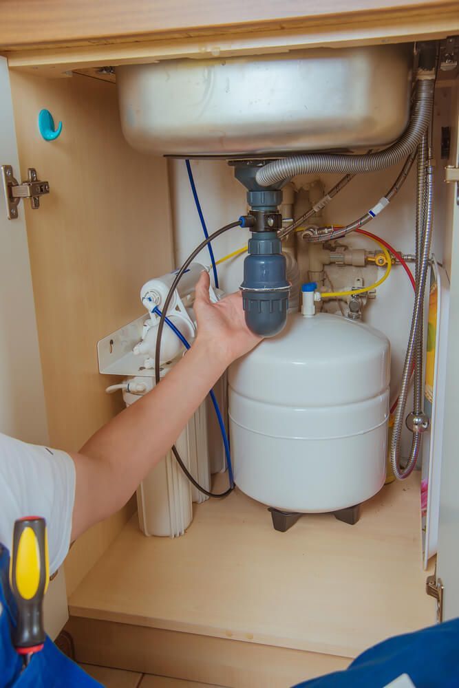 Man fixing a water filter under a sink — Water Filtration Systems in Mackay, QLD