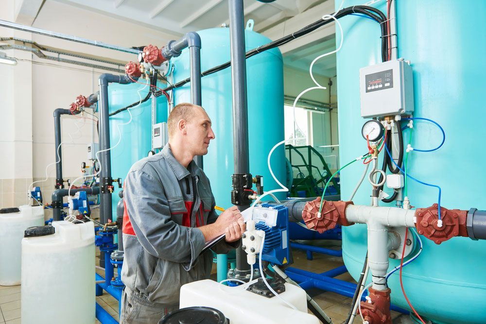 A Man Is Working On A Machine In A Factory — Eureka Water & Filtration In Mount St John, QLD