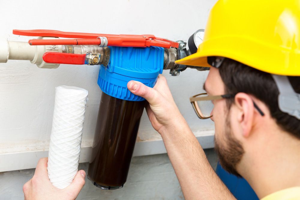A Man Wearing A Hard Hat Is Fixing A Water Filter — Eureka Water & Filtration In Mount St John, QLD