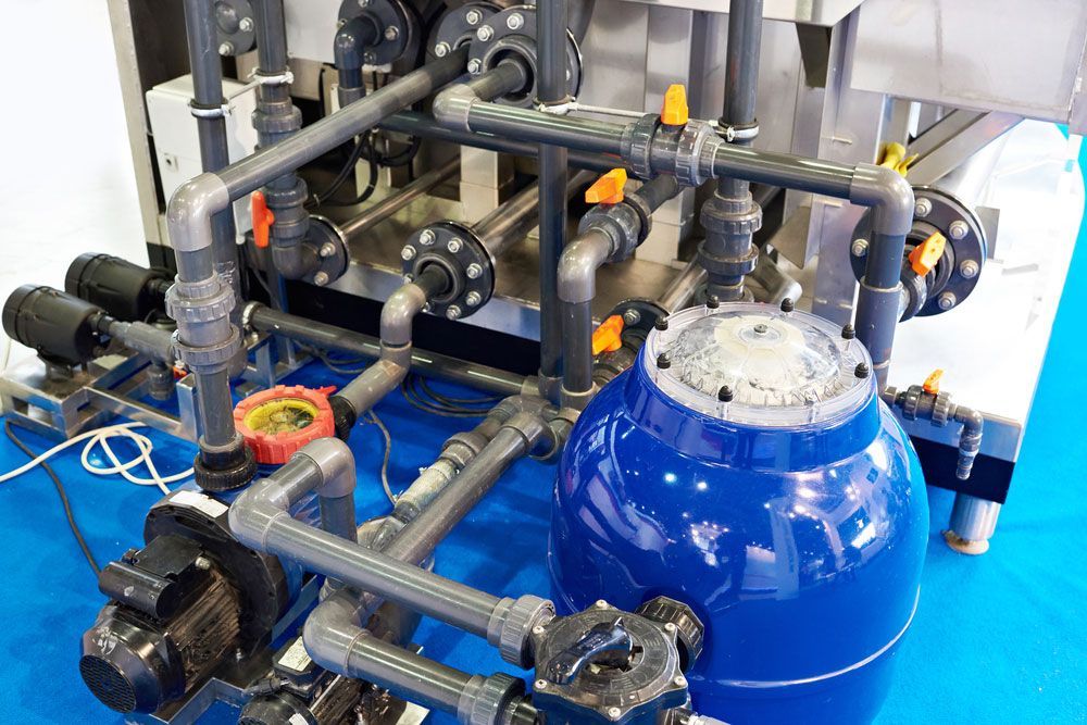 A Blue Tank Is Sitting On Top Of A Machine With Lots Of Pipes — Eureka Water & Filtration In Mount St John, QLD