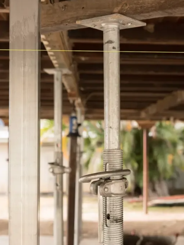 A Row of Metal Poles Are Sitting Under a Wooden Roof — Wilson's House Restumping in Northern Rivers, NSW