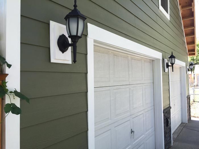 A garage with a green siding and white garage doors