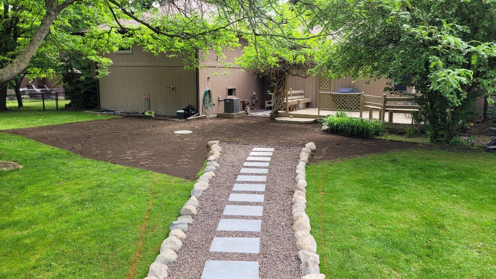A stone walkway leading to a house in a backyard.