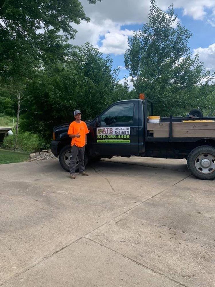 A man in an orange shirt is standing in front of a truck.