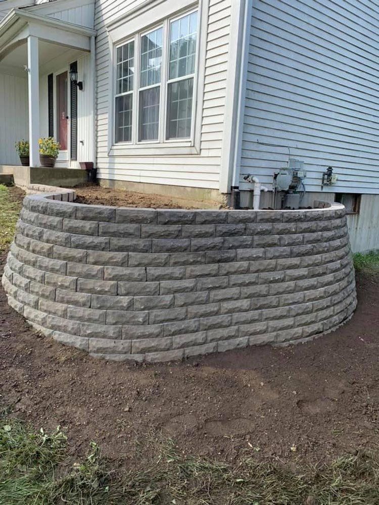 A man in an orange shirt is standing in front of a truck. landscape design