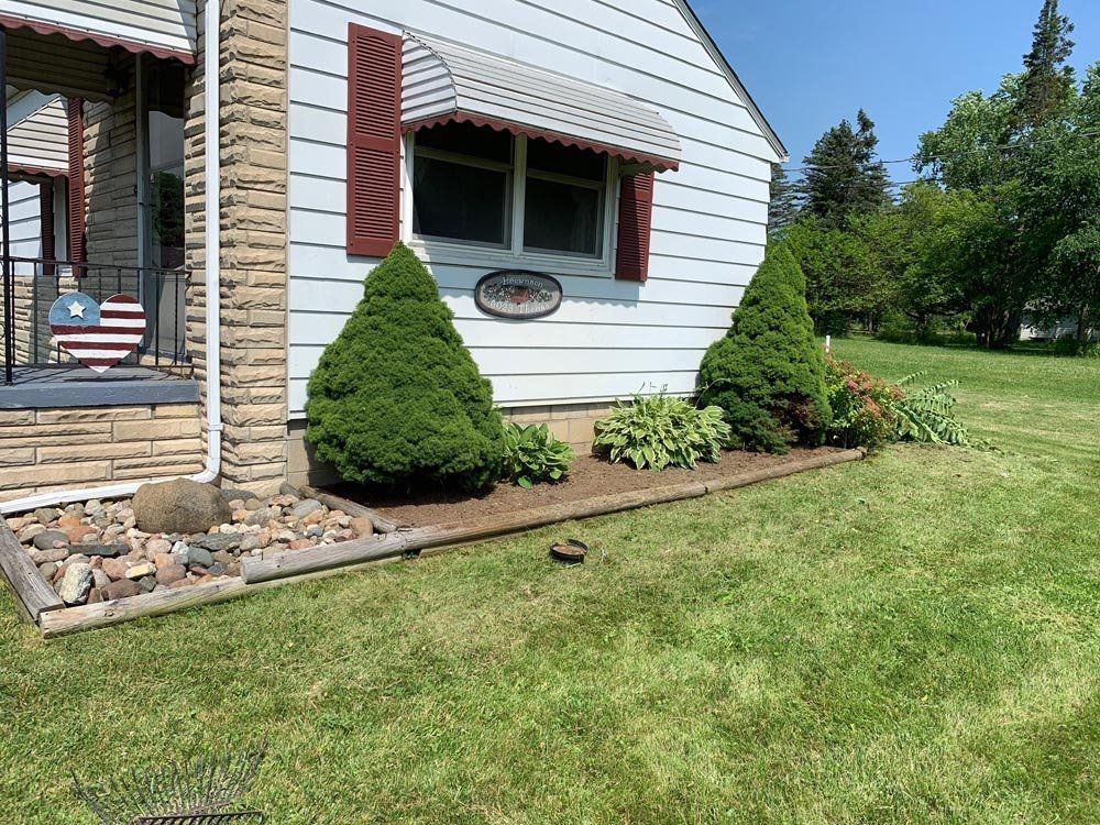 A house with a lot of windows is sitting on top of a lush green lawn. landscape