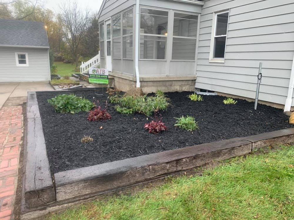 A house with a screened in porch and a garden in front of it. mulch
