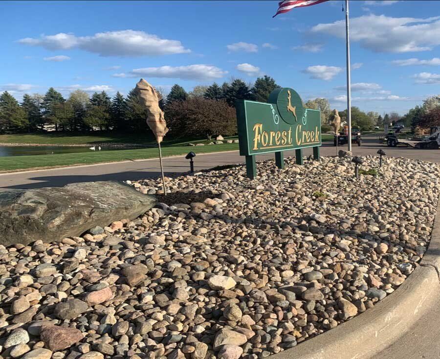A sign on the side of a road that says forest creek. landscape 