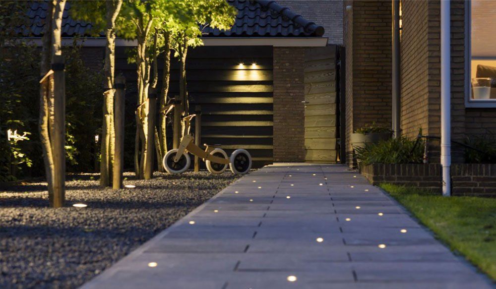 A walkway leading to a house is lit up at night. LANDSCAPE LIGHTING