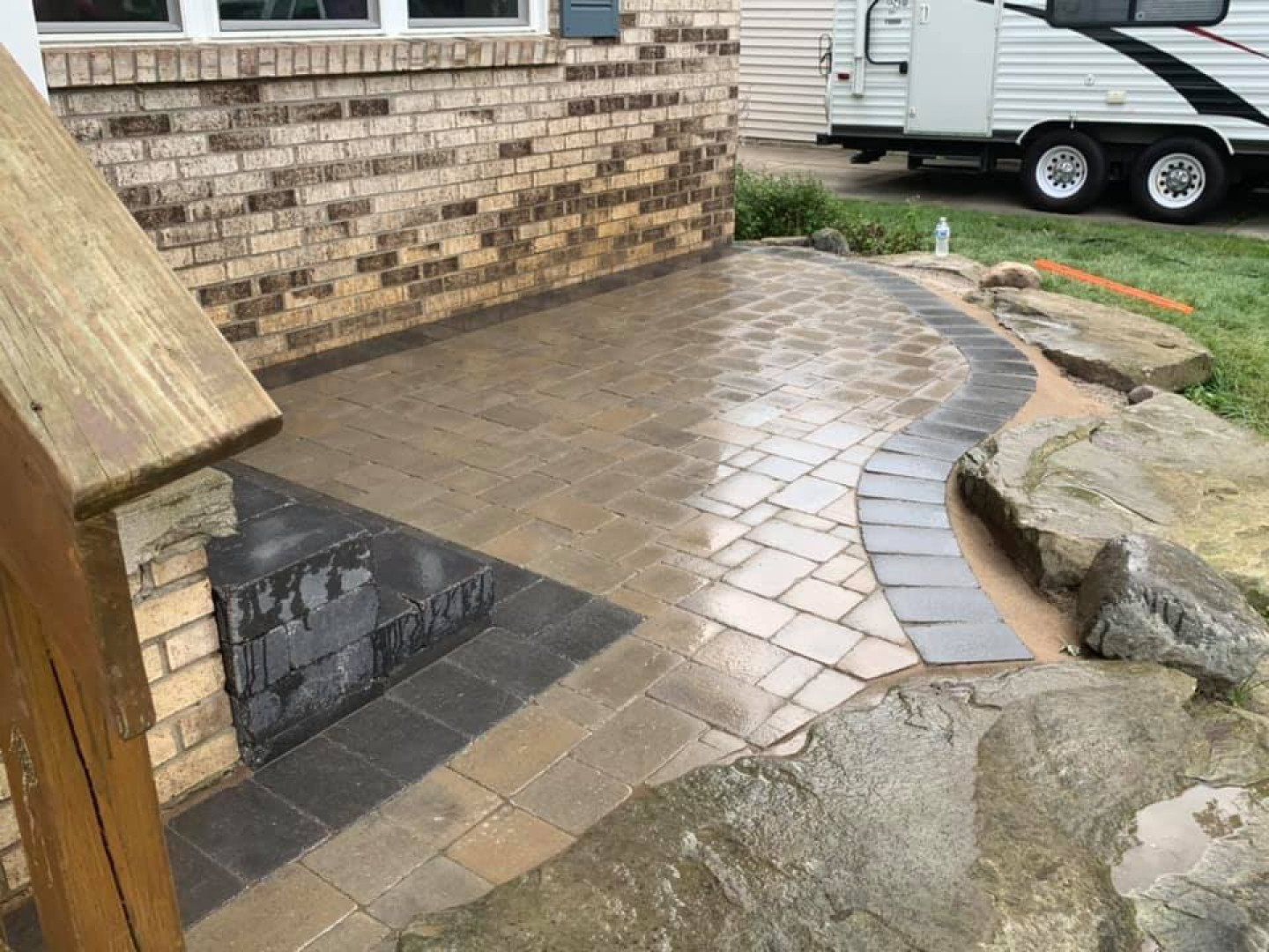 A brick house with a patio and a rv parked in front of it.