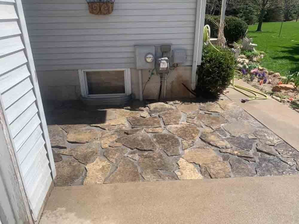 A stone walkway leading to the basement of a house.