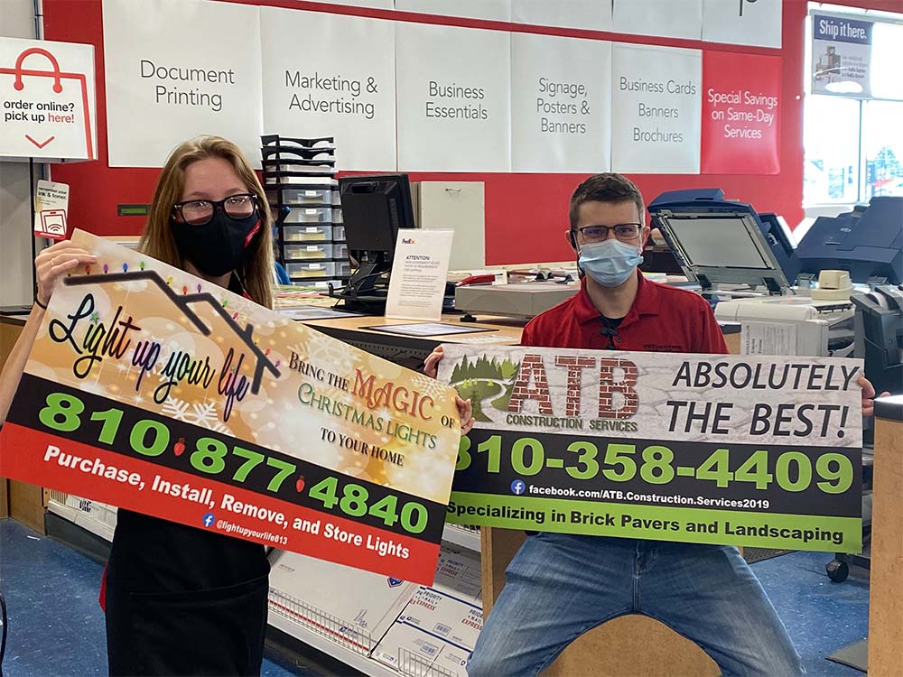 A man and a woman wearing masks are holding a sign in a store. business