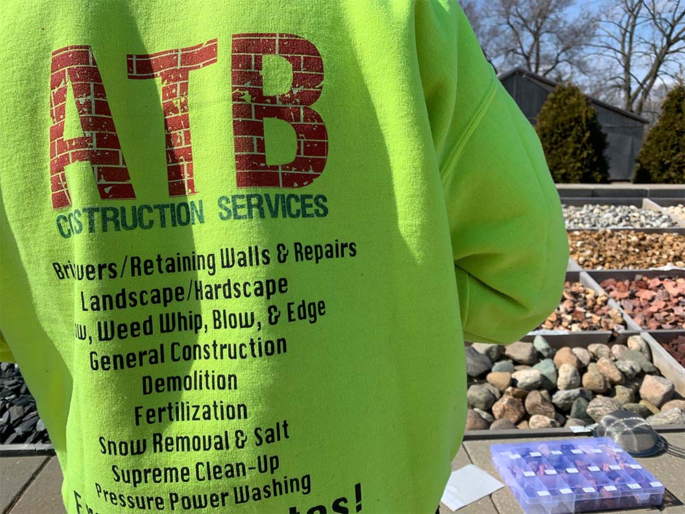 A person wearing a green sweatshirt that says atb construction services