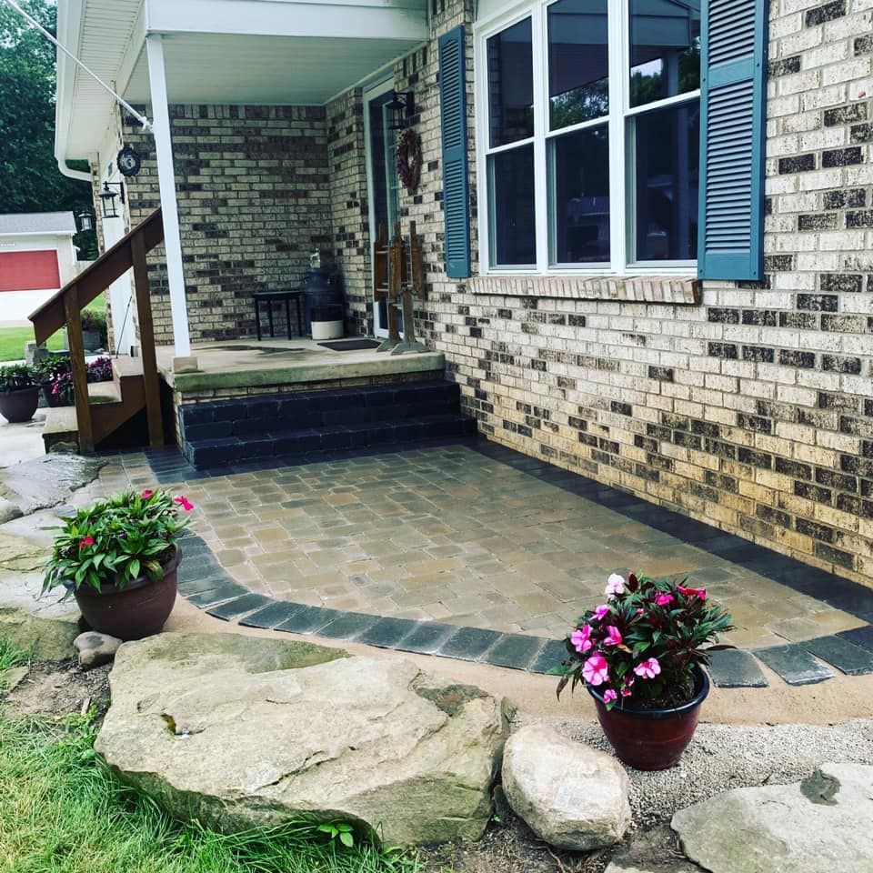 A brick planter with a tree in it in front of a brick house. retaining wall
