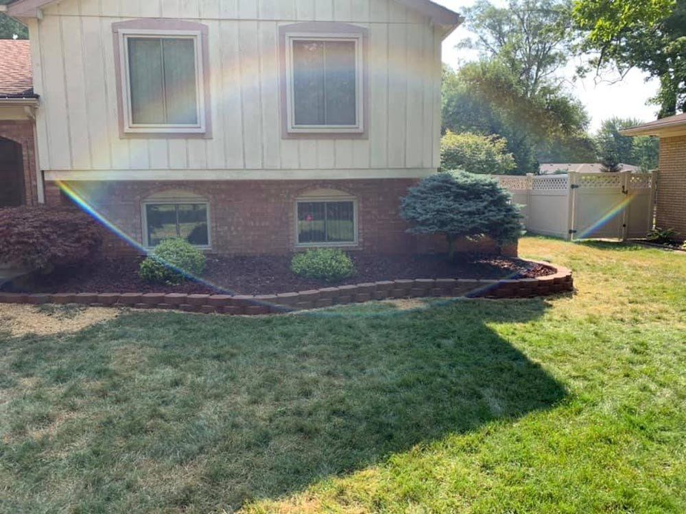 A brick house with a patio and flowers in front of it. brick paver patio