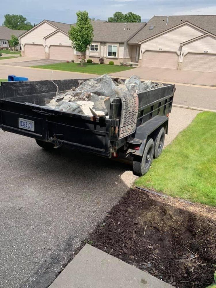 A dump truck is parked on the side of the road in front of a house. junk removal