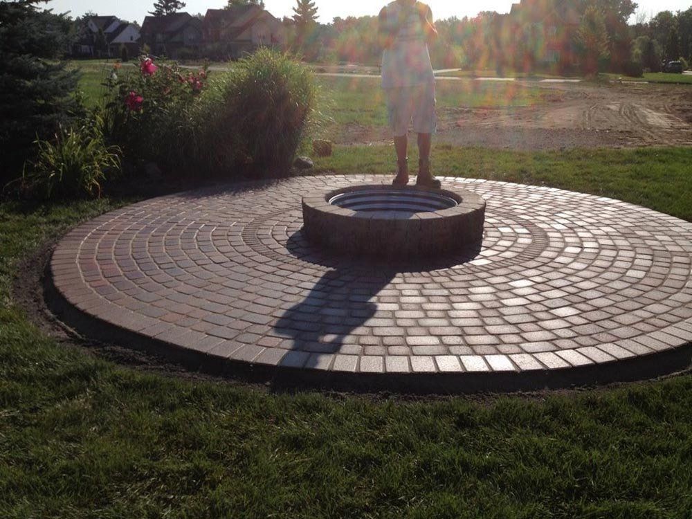 A woman is standing in front of a fire pit in a circle.
