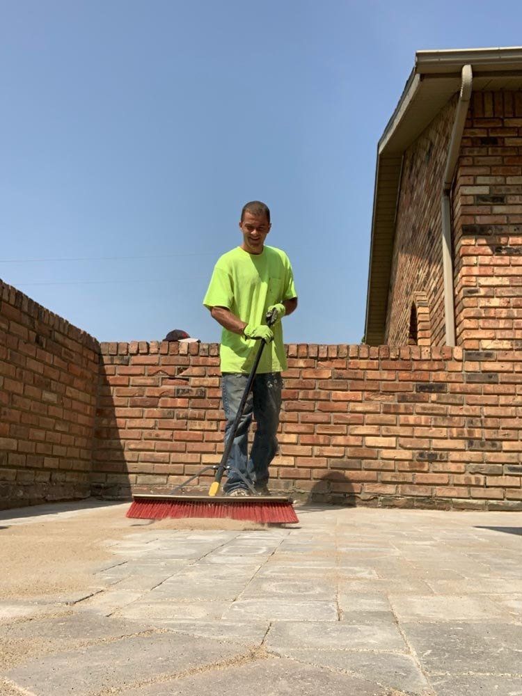 A man is kneeling down on a roof holding a spatula. downspouts