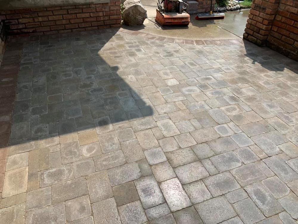 A brick patio with a brick wall in the background. brick paver patio
