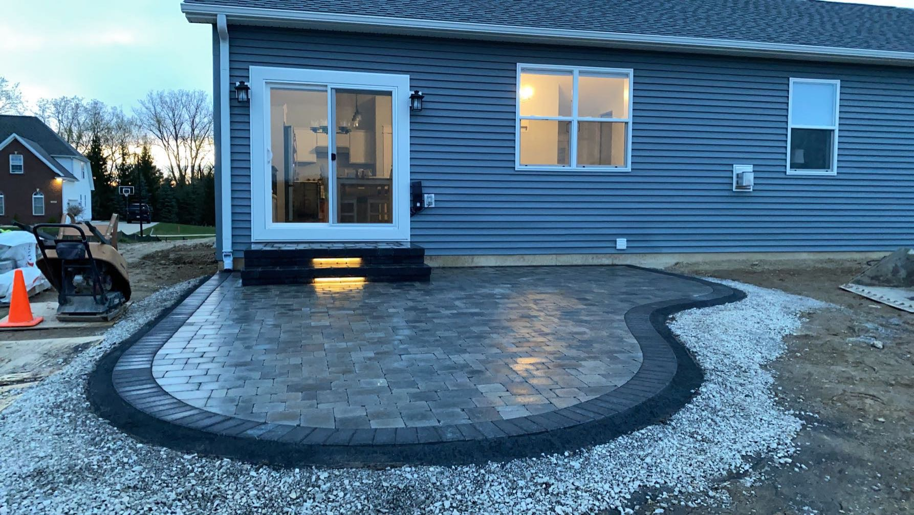 A house with a patio in front of it. brick paver patio