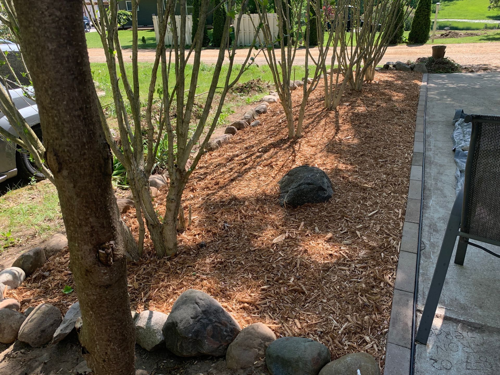 A man is walking down a dirt road next to a yellow bucket. mulch