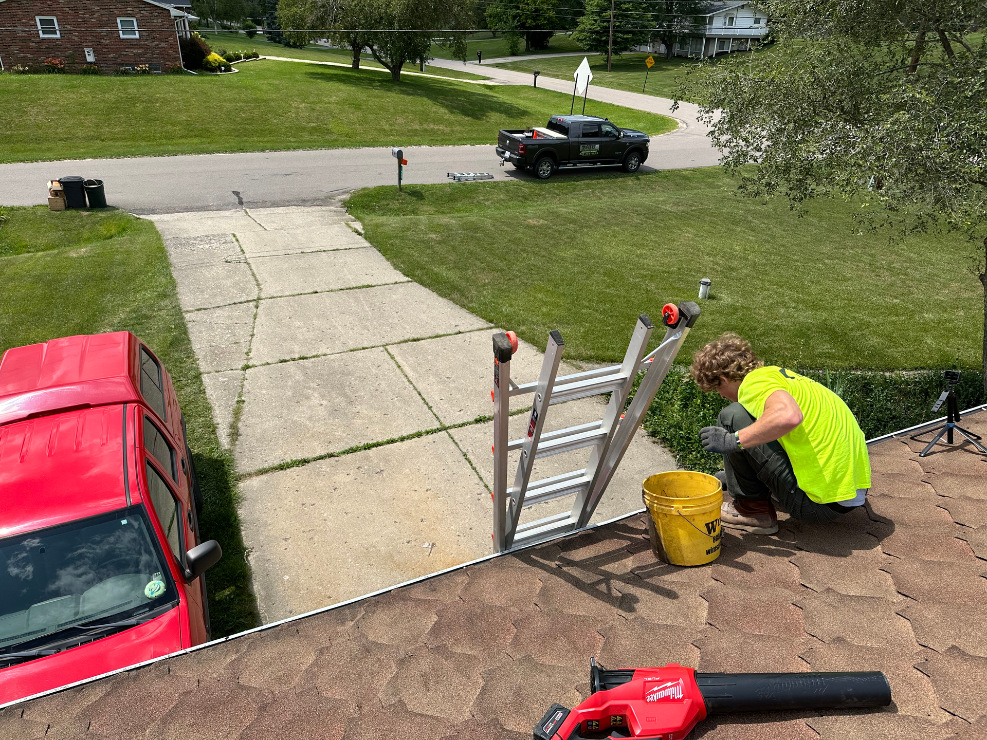 A man is cutting a tree with a chainsaw while standing on a ladder. tree trimming