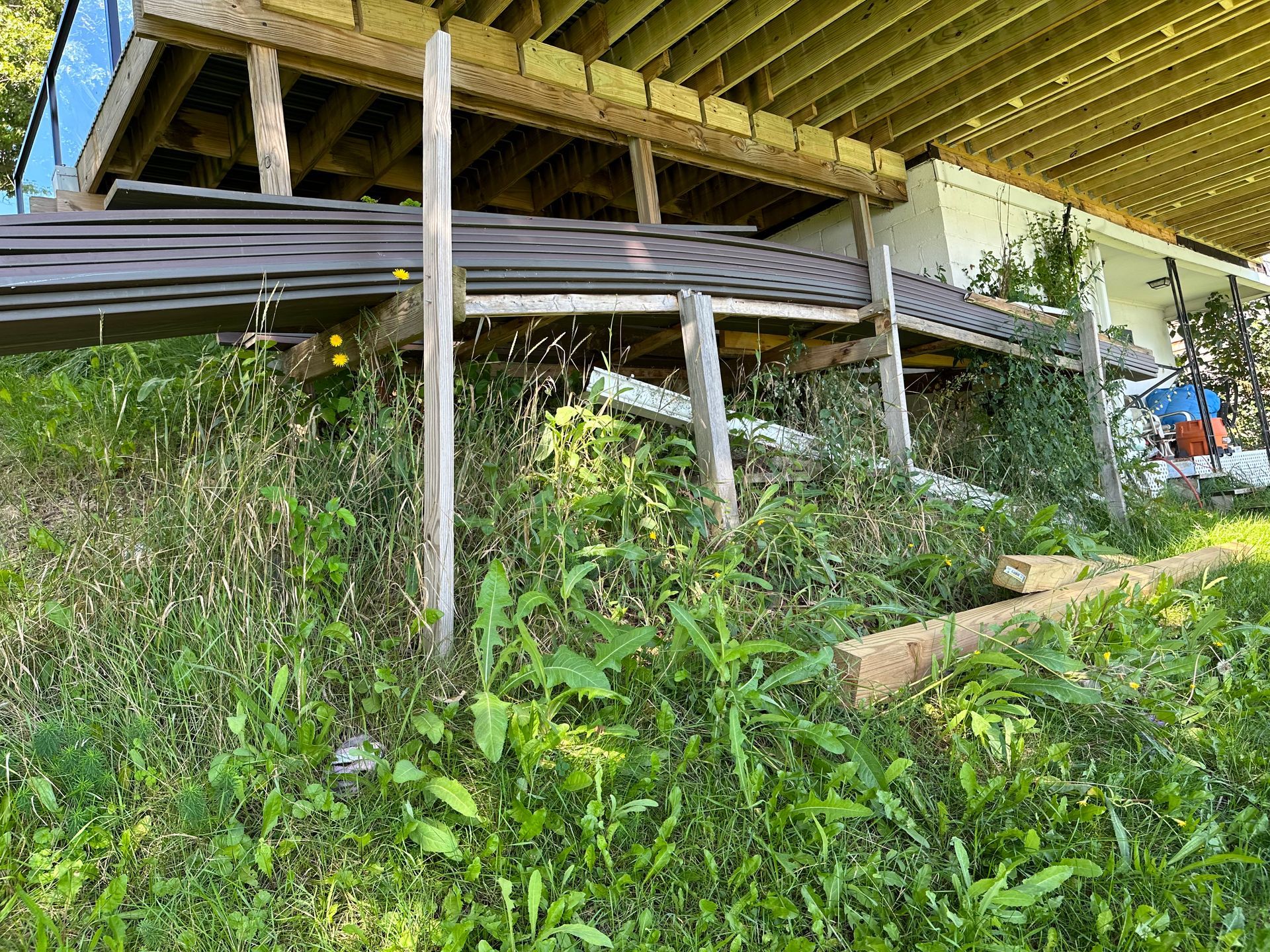 a wooden deck is sitting on top of a grassy hill next to a house .