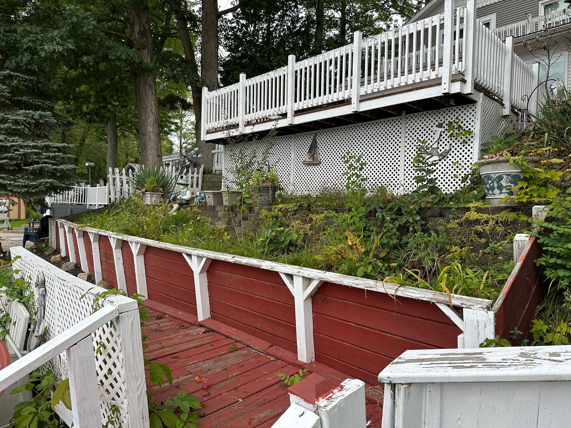 a white fence is surrounded by plants and rocks in a garden .